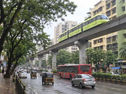 The monorail passing on its single beam above a tree-lined road in Chembur